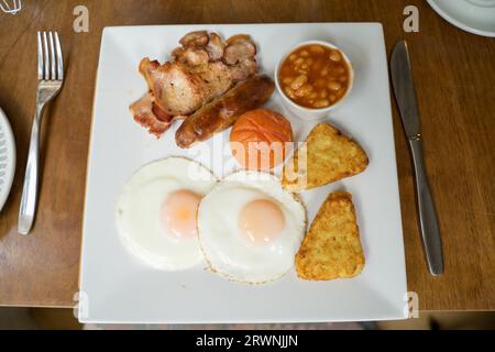 Komplettes englisches Frühstück auf einem Teller, Speck, Wurst, sonnige Spiegeleier, Kartoffelrösti, gebratene Tomaten, England UK Stockfoto