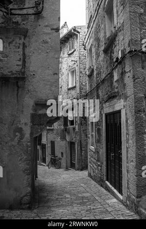 Eine ruhige Straße im historischen Zentrum der mittelalterlichen Küstenstadt Rovinj, Istrien, Kroatien. Die Gebäudefront links hat einen Jet-Ting mit Bogenstütze Stockfoto