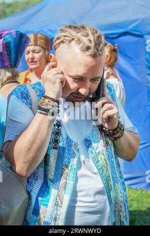 Kolomna, Russland, 12. Juni 2022. Ein junger Mann mit Dreadlocks in slawischer Nationalkleidung spricht an einem Sommertag am Telefon. Stockfoto