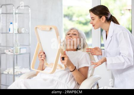 Der ältere Patient sieht in der Klinik in den Spiegel. Stockfoto