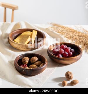 Traditionelle handgefertigte Holzschale mit Walnüssen und Trauben auf dem Tisch Stockfoto