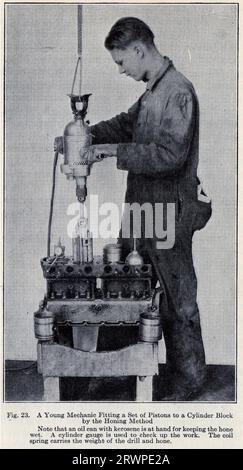Halbton eines jungen Mechanikers, der einen Satz Kolben mit dem Honverfahren an einen Zylinderblock anbringt, ca. 1935 Stockfoto