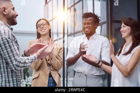 Lachende, multiethnische Geschäftsleute, die im Büro reden. Stockfoto