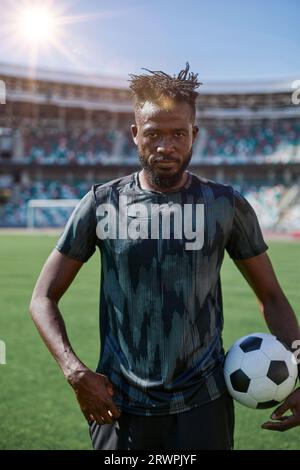 Ein junger Mann steht in einem Stadion mit einem Fußball in der Hand Stockfoto