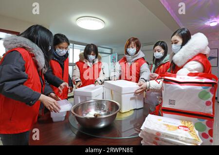 LUANNAN COUNTY, China - 14. Februar 2022: Junge Freiwillige packen Knödel um und bereiten sich darauf vor, sie am Vorabend des zu verteilen Stockfoto