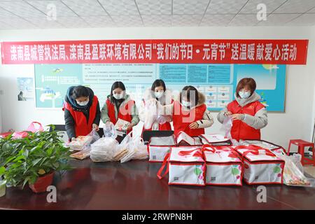 LUANNAN COUNTY, China - 14. Februar 2022: Junge Freiwillige packen Knödel um und bereiten sich darauf vor, sie am Vorabend des zu verteilen Stockfoto