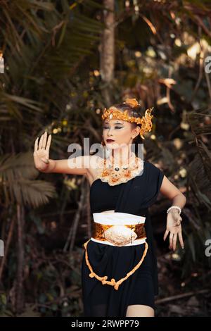 Balinesische Frau trägt eine goldene Krone und eine goldene Halskette in ihrem Make-up mit einem schönen Gesicht im Wald Stockfoto