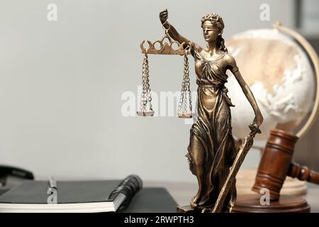 Figur der Lady Justice, Gavel, Globus und Notizbücher im Innenbereich, Platz für Text. Symbol der gerechten Behandlung nach dem Gesetz Stockfoto