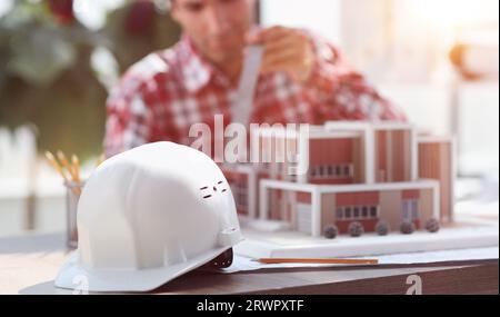 Bauhelm auf dem Tisch vor dem Hintergrund des Architekten Stockfoto