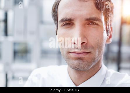 Porträtaufnahme eines seriösen, konzentrierten Geschäftsmannes, der ein weißes Hemd trägt und in die Kamera schaut. Stockfoto