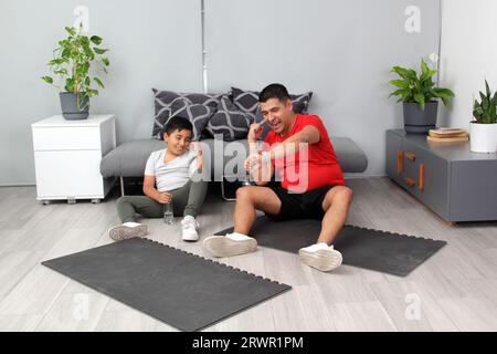 Übergewichtiger Latino Vater und Sohn feiern Rekord für Zeit Sport zu Hause, um ihre Gesundheit zu verbessern Stockfoto