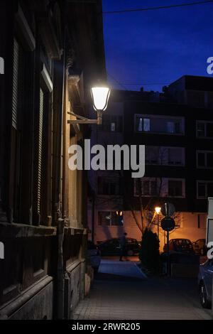 Bild einer Straßenlaterne in einer Straße, nachts, mit einer Wohnstraße von Novi Sad, Serbien im Hintergrund, die ein weißes Licht projiziert. Stockfoto