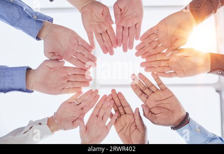Junge Freiwillige legen ihre Hände wie ein echtes Team aufeinander, während sie im Büro einer Wohltätigkeitsorganisation stehen Stockfoto