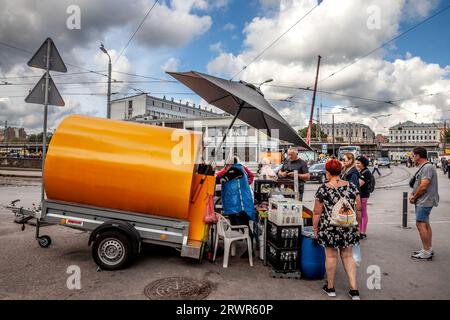 Bild einer Frau, die Kvas in einer Straße von Riga, Lettland, verkauft. Kvass ist ein traditionelles slawisches und baltisches fermentiertes Getränk, das üblicherweise aus Roggenbrot hergestellt wird Stockfoto