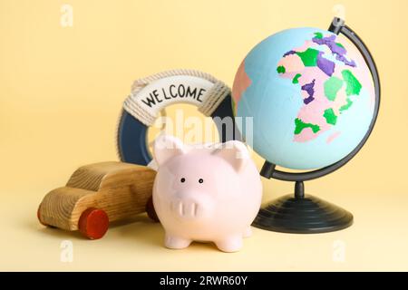 Sparschweinbank, Kugel, Holzauto und Ringboje auf beigem Hintergrund Stockfoto