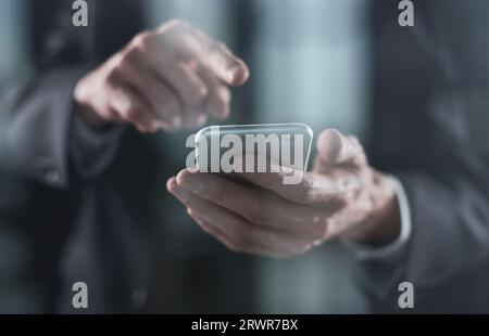 Smartphone in den Händen eines jungen Mannes auf schwarzem Hintergrund. Schreiben Sie Text mit den Fingern. Stockfoto