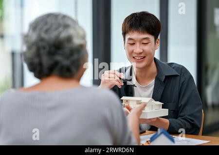 Ein glücklicher und professioneller asiatischer männlicher Architekt oder Innenarchitekt berät mit einem Kunden im Büro bei der Planung eines Gebäudes. Stockfoto