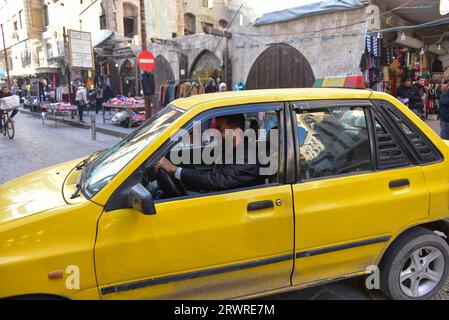 Ein freundlicher Taxifahrer verlangsamte sein gelbes Taxi, um mit einem großen Lächeln im Gesicht fotografiert zu werden, in Hama, Syrien Stockfoto