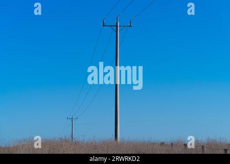 Abstrakte Stromleitungen und Pole isolierte Ansicht mit einem blauen Himmel Hintergrund in der ländlichen Gegend Victoria Australien. Stockfoto