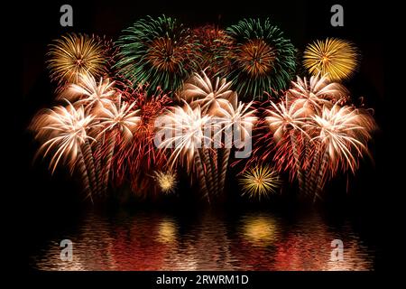 Buntes Feuerwerk und der Hintergrund des Nachthimmels mit Reflexion auf dem Wasser. Stockfoto