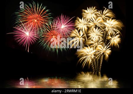 Buntes Feuerwerk und der Hintergrund des Nachthimmels mit Reflexion auf dem Wasser. Stockfoto