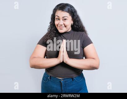 Lächelndes Mädchen, das um einen Gefallen bittet. Glückliche Menschen, die um einen Gefallen bitten. Wunderschönes lateinisches Mädchen, das isoliert um einen Gefallen bittet Stockfoto