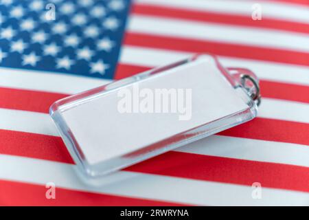 Ein glänzender Schlüsselanhänger mit einem weißen Etikett für Text auf dem Hintergrund der US-Flagge. Speicherplatz kopieren. Stockfoto