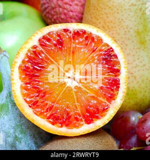 Schneiden Sie die Blutorange mit anderen Früchten im Hintergrund ab Stockfoto