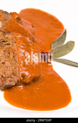 Hackbraten in Scheiben, garniert mit Sauce und Salbeiblättern Stockfoto