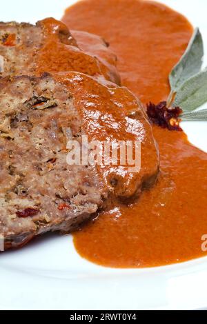 Hackbraten in Scheiben, garniert mit Sauce und Salbeiblättern Stockfoto