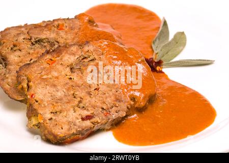 Hackbraten in Scheiben, garniert mit Sauce und Salbeiblättern Stockfoto