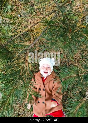 Ein kleines Kind liegt auf dem Boden und lächelt. Draufsicht. Das Konzept der Herbstblätter für Kinder. Ein Lächeln im Gesicht eines Kindes. Ein kleines Kind in einem Stockfoto