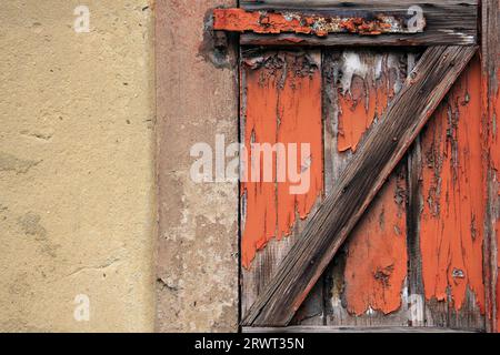 Früher orange lackierter Holzverschluss an Hauswand, Detail Stockfoto