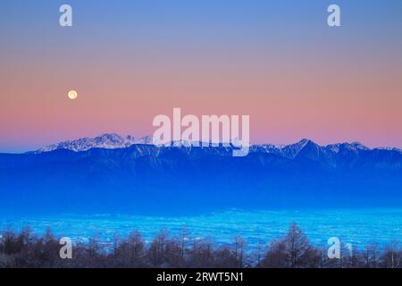 Hotaka-Gebirge und Vollmond am Morgen, vom Takabotchi-Plateau aus gesehen Stockfoto