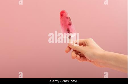 Die Frau hält einen Eiskegel auf rosafarbenem Hintergrund. . Hochwertige Fotos Stockfoto