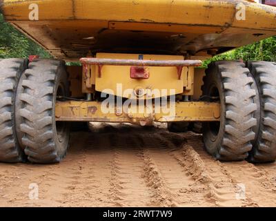 Die Rückseite eines Baggers, der auf beigem Sand steht, Spuren des Baggers darunter Stockfoto