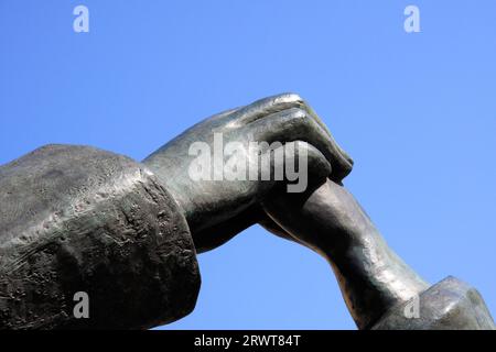 Detail einer Bronzeskulptur, männliche und weibliche Hand verbunden, Hintergrund blauer Himmel Stockfoto