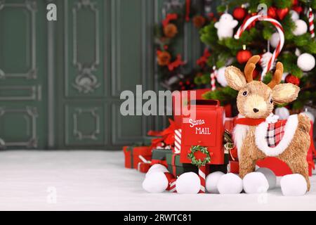 Weihnachtsbanner mit Rentier, roter weihnachtsmann-Postkasten und Geschenkboxen vor dem Baum mit grünem Hintergrund und Kopierraum Stockfoto