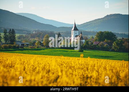 Atemberaubende Frühlingslandschaft: Kirche eingerahmt von lebendiger gelber Rapslandschaft Stockfoto