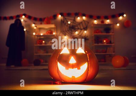 Die gruselige traditionelle Jack-o-Laterne auf dem Boden im mystischen Zimmer des Hauses leuchtet nachts. Stockfoto
