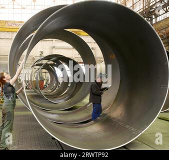 PRODUKTION - 24. August 2023, Sachsen, Leipzig: Bei der SIAG Tube&Tower GmbH prüfen Mitarbeiter die Schweißnähte und Oberflächen eines Stahlrohrsegments für Windturbinen. Aufgrund der langen Genehmigungsverfahren für Schwerlasttransporte zu Windparks und der daraus resultierenden erschöpften Lagerkapazitäten musste die Produktion in den letzten Monaten eingeschränkt werden. Derzeit hoffen die Mitarbeiter auf wesentlich kürzere Bearbeitungszeiten bei den Behörden und eine Lösung des Transportrückstands. Ziel ist es, die Produktion langsam wieder anzukurbeln und Kurzarbeit für Anlageningenieure zu vermeiden. Das Unternehmen, das einer der führenden Anbieter ist Stockfoto