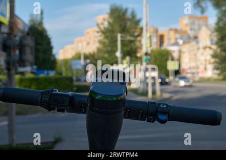 Das Lenkrad eines Elektrorollers, der auf einer Stadtstraße steht. Nahaufnahme Stockfoto