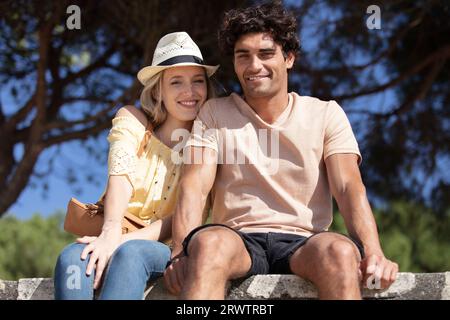 Ein Multi-Rassen-Paar, das an einer Wand sitzt Stockfoto
