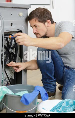 Mann, der versucht, eine Waschmaschine zu reparieren Stockfoto