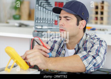 Elektriker prüft Spannung auf Küchenplaketten Stockfoto