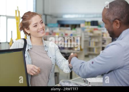 afroamerikanischer Mann, der die Hand des Kunden im Laden schüttelt Stockfoto