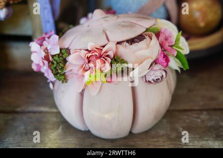 Schöne Blumenkomposition im rosa Kürbis auf Holztisch Stockfoto