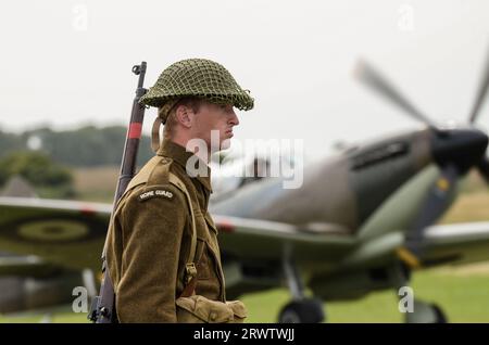 Young Home Guard-Reenactor bei einer Airshow mit einem Supermarine Spitfire-Kampfflugzeug aus dem Zweiten Weltkrieg. Die Nachstellung eines Flugplatzes Stockfoto