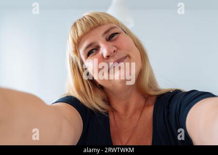 Portrait Frau mittleren Alters, blond, grimmierend im Frontspiegel Stockfoto