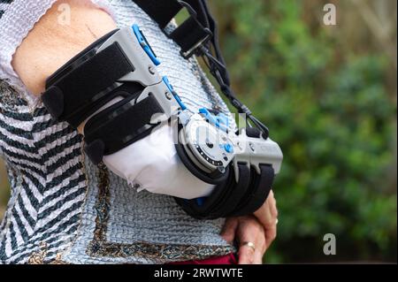 Ältere Frau mit Ossur Rebound Post-OP-Ellenbogenstütze, nachdem sie ihren Ellenbogen gebrochen und operiert wurde. Er ermöglicht die Einstellung für eingeschränkte Bewegung. Stockfoto